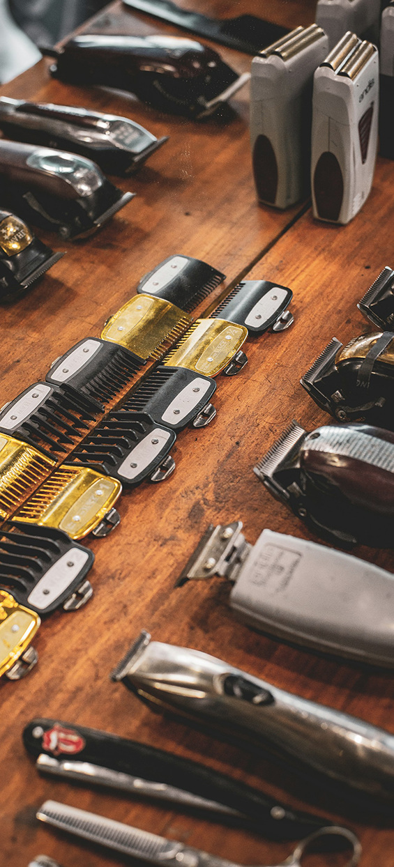 Barber clippers, trimmers and guards laid out on a wooden counter