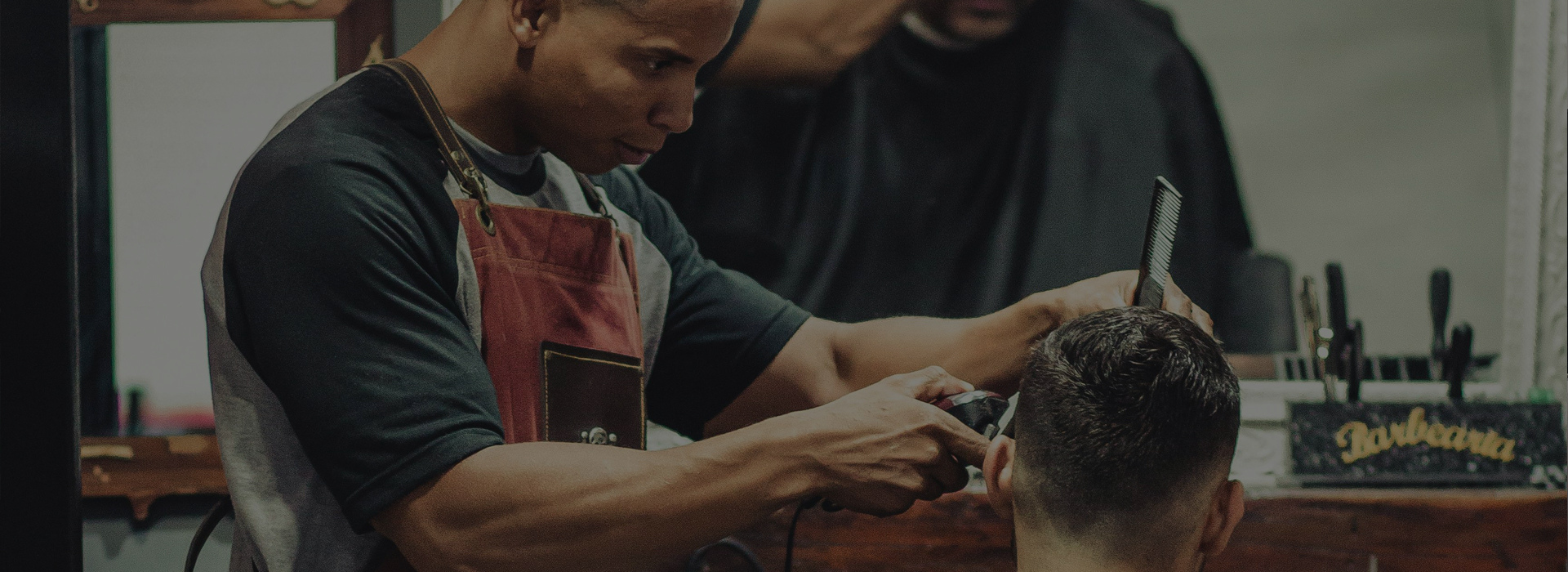 Barber cutting a client's hair with clippers and a comb